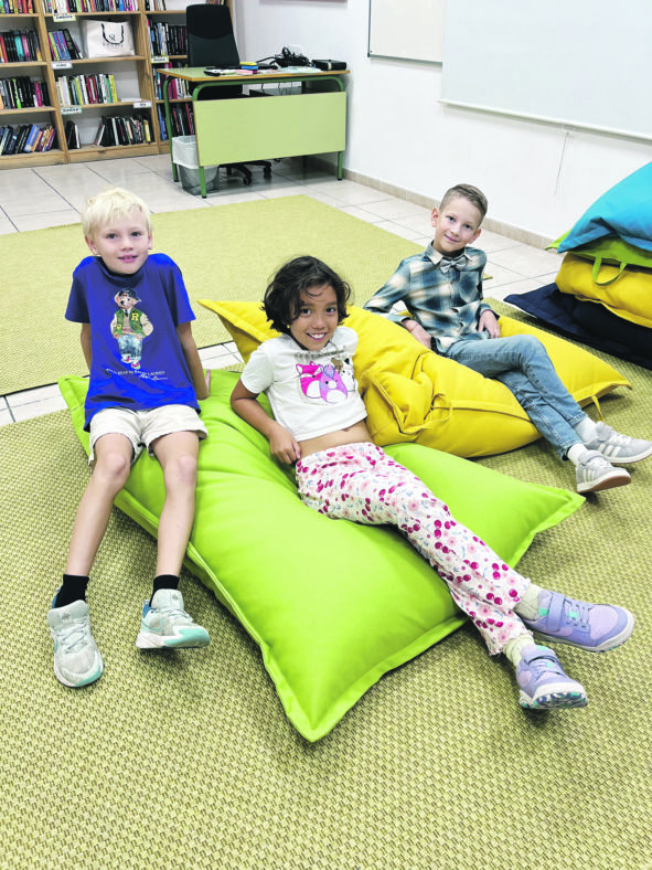 iloisia lapsia istuvat maassa tyynyjen päällä.
